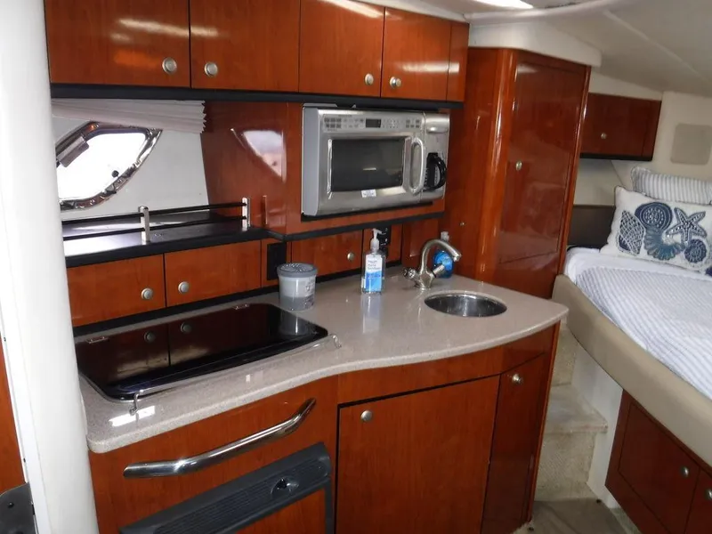 Slide: The Image of 2007 Sea Ray 310 interior with kitchenette, microwave, sink, and cozy sleeping area. - 8