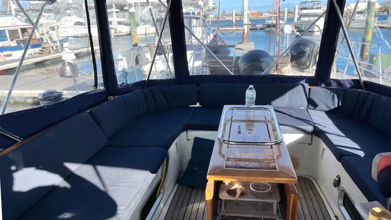 Slide: The Image of Cockpit of 2005 Beneteau 57 yacht with blue seating and wooden table, docked at marina. - 13