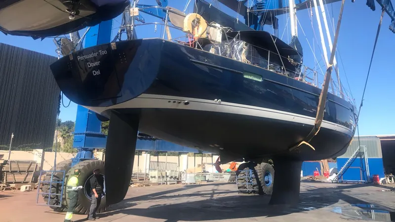 Slide: The Image of 2005 Beneteau 57 yacht in dry dock, undergoing maintenance under clear blue skies. - 14