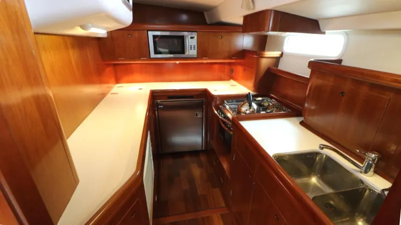 Slide: The Image of Luxurious 2005 Beneteau 57 yacht kitchen with wood cabinetry and modern appliances. - 5