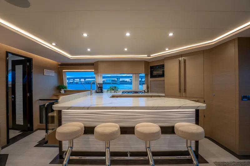 Slide: The Image of Luxurious yacht interior with modern kitchen, bar stools, and ambient lighting, Horizon PC60 2020 model. - 12