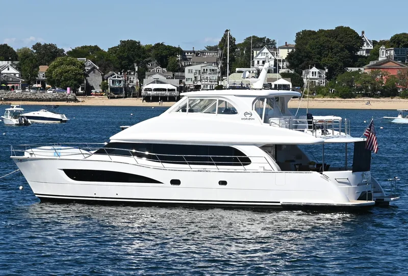 Slide: The Image of Luxury Horizon PC60 yacht on water, 2020 model, with coastal homes in the background. - 2