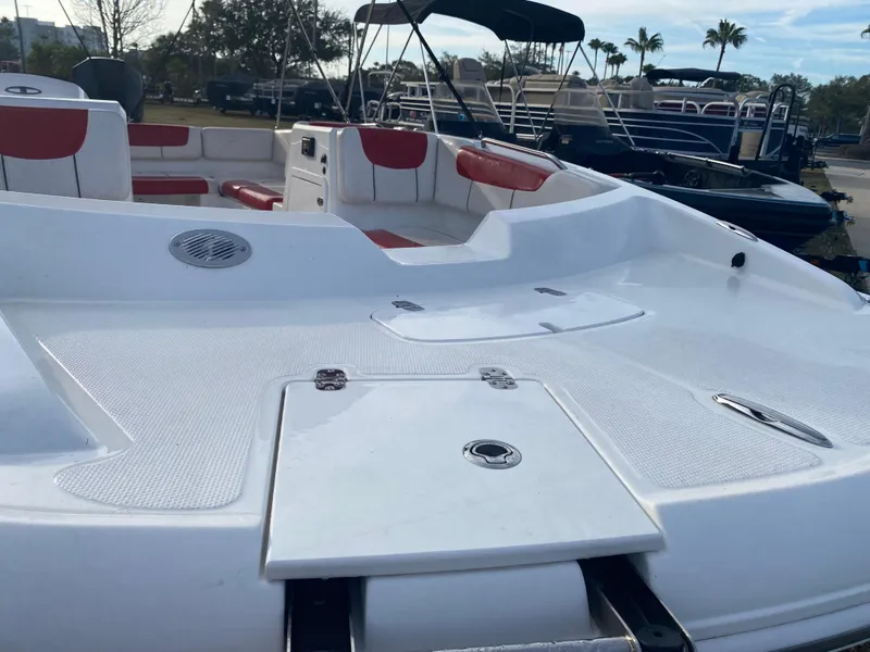 Slide: The Image of 2022 Tahoe 2150 boat with white deck and red seating, docked outdoors. - 2