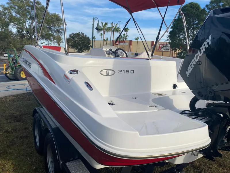 Slide: The Image of 2022 Tahoe 2150 boat with Mercury engine, red and white design, parked outdoors. - 3