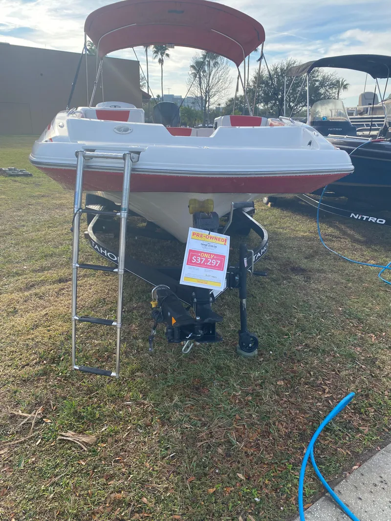 Slide: The Image of 2022 Tahoe 2150 boat on display with price sign, ladder, and red canopy. - 5