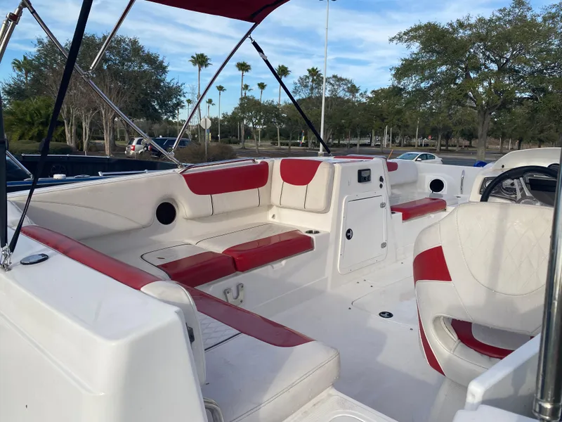 Slide: The Image of 2022 Tahoe 2150 boat interior with red and white seating, parked outdoors. - 8