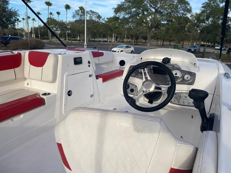 Slide: The Image of 2022 Tahoe 2150 boat interior with red and white seating, steering wheel, and dashboard. - 9