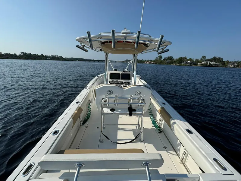Slide: The Image of 2018 Edgewater 245CC boat on calm water, featuring a spacious deck and fishing rod holders. - 21