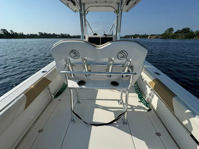 Slide: The Image of 2018 Edgewater 245CC boat interior, featuring seating and rod holders on a calm lake. - 22