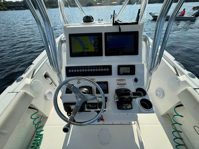 Slide: The Image of Edgewater 245CC 2018 boat dashboard with navigation screens and steering wheel on water. - 27