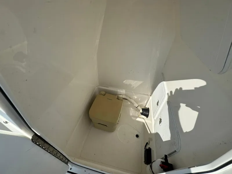 Slide: The Image of 2018 Edgewater 245CC boat interior with portable toilet and storage compartment. - 32