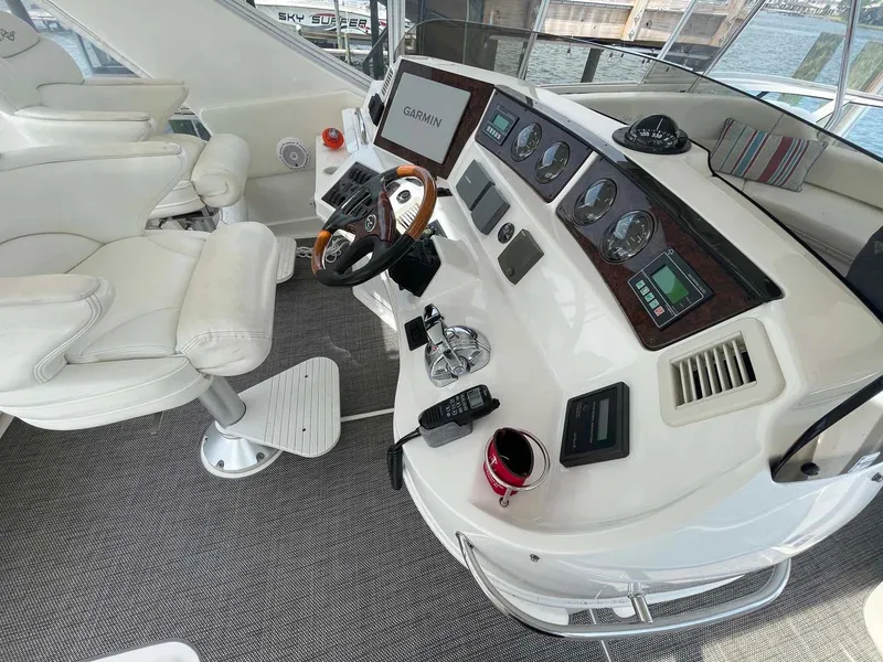 Slide: The Image of 2003 Sea Ray 560 Sedan Bridge helm with Garmin navigation, white seating, and control panel. - 11