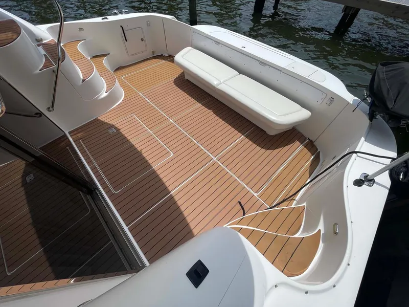 Slide: The Image of 2003 Sea Ray 560 Sedan Bridge yacht deck with teak flooring and white seating. - 17