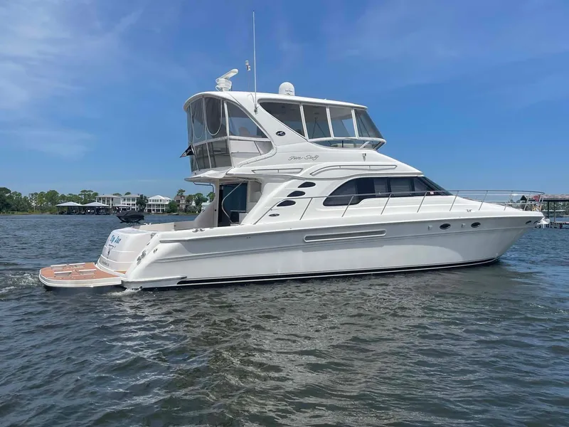 Slide: The Image of 2003 Sea Ray 560 Sedan Bridge yacht on calm water under clear blue sky. - 2