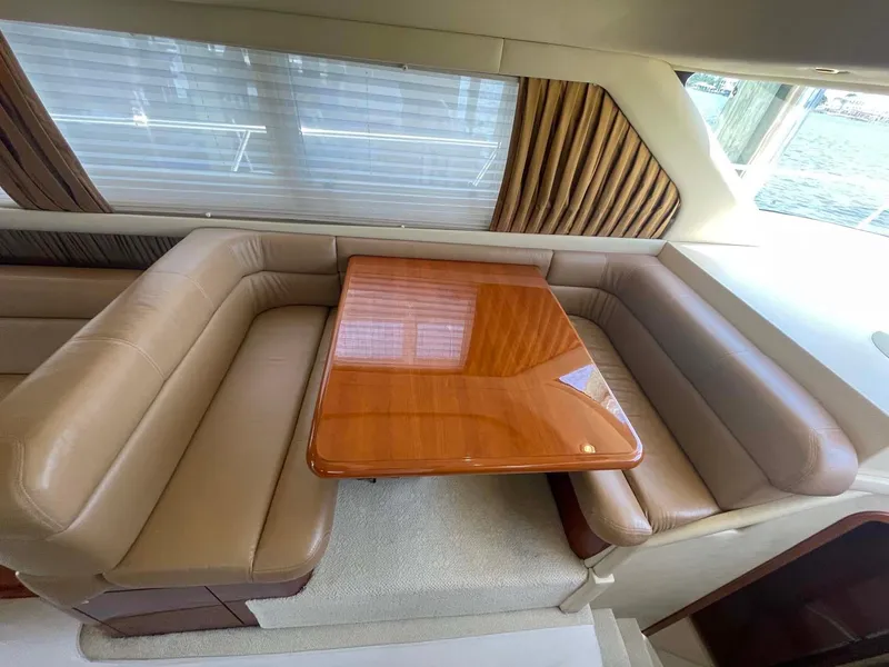Slide: The Image of Luxurious interior of 2003 Sea Ray 560 Sedan Bridge with leather seating and wooden table. - 27