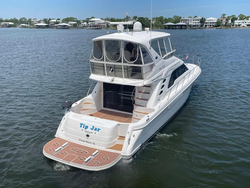 Slide: The Image of 2003 Sea Ray 560 Sedan Bridge yacht on water, rear view, with "Tip Jar" name visible. - 3