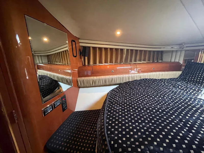 Slide: The Image of 2003 Sea Ray 560 Sedan Bridge cabin interior with patterned bedding and wood accents. - 36