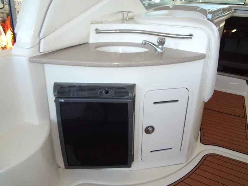 Slide: The Image of 2005 Sea Ray 320 Sundancer boat kitchenette with sink, mini fridge, and storage cabinet. - 10