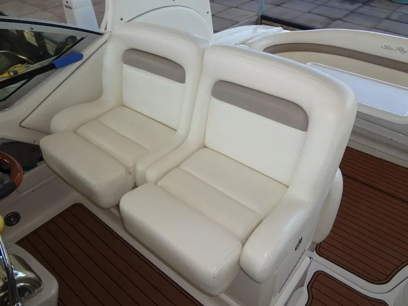 Slide: The Image of 2005 Sea Ray 320 Sundancer boat seats with white upholstery and wooden flooring. - 12