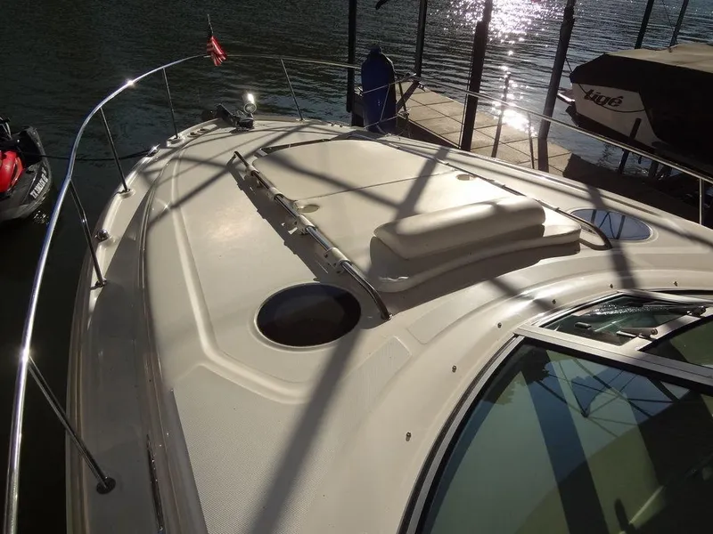 Slide: The Image of 2005 Sea Ray 320 Sundancer boat deck with sun pad, docked by the water. - 21
