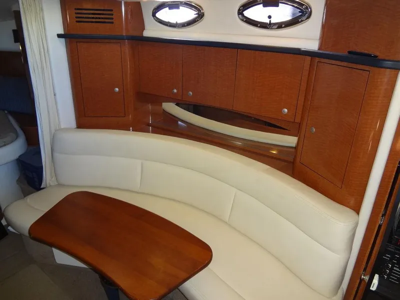 Slide: The Image of 2005 Sea Ray 320 Sundancer interior with curved seating and wooden table. - 25
