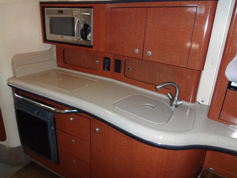 Slide: The Image of 2005 Sea Ray 320 Sundancer kitchen with wood cabinets, sink, and microwave. - 30