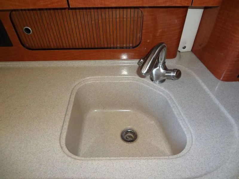 Slide: The Image of 2005 Sea Ray 320 Sundancer kitchen sink with modern faucet and wooden cabinetry. - 32