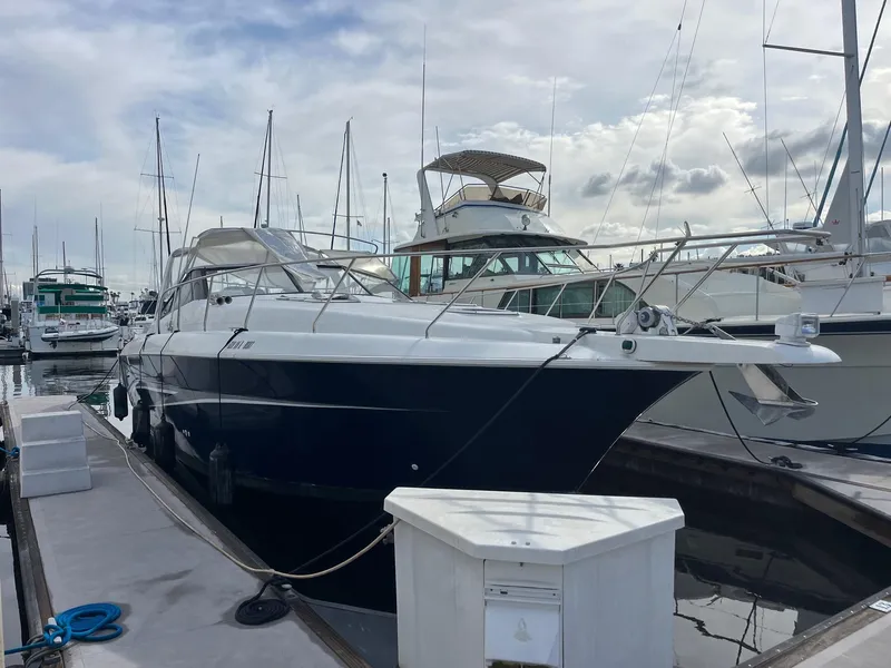 The Image of 1993 Silverton 38 Express yacht docked at marina under cloudy sky. - 1