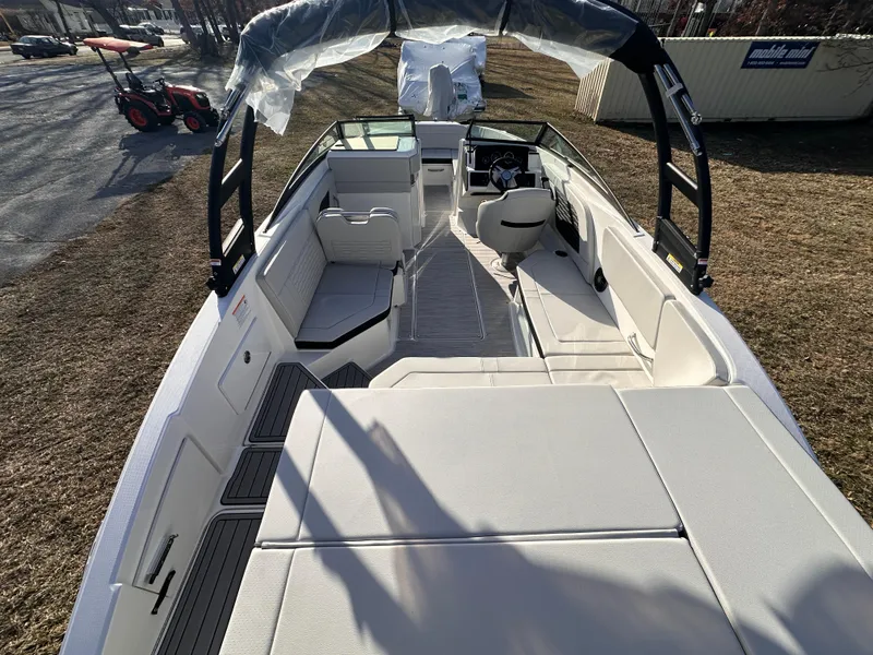Slide: The Image of 2025 Sea Ray SPX 230 OB boat interior with seating and helm, parked on grass. - 6