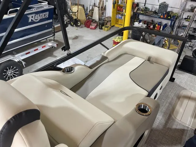 Slide: The Image of 2025 SunCatcher Select 322SS boat interior with beige seating and cup holders in a workshop. - 15