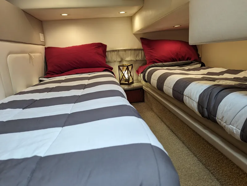 Slide: The Image of 1999 Maxum 4100 SCB cabin with twin beds, striped bedding, and red pillows. - 24