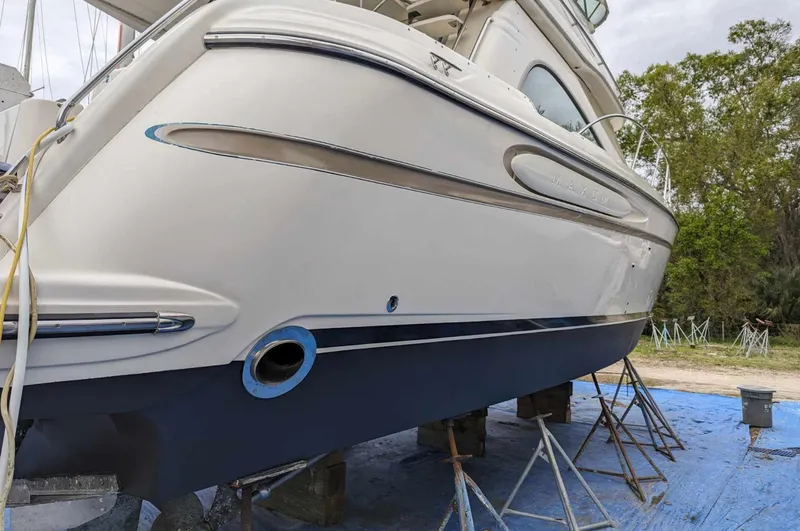 Slide: The Image of 1999 Maxum 4100 SCB yacht on dry dock, side view, with trees in the background. - 29