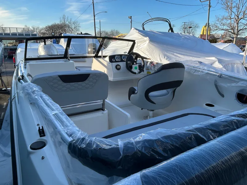 Slide: The Image of 2024 Bayliner Element M19 boat interior with steering wheel and seating, wrapped in protective plastic. - 7