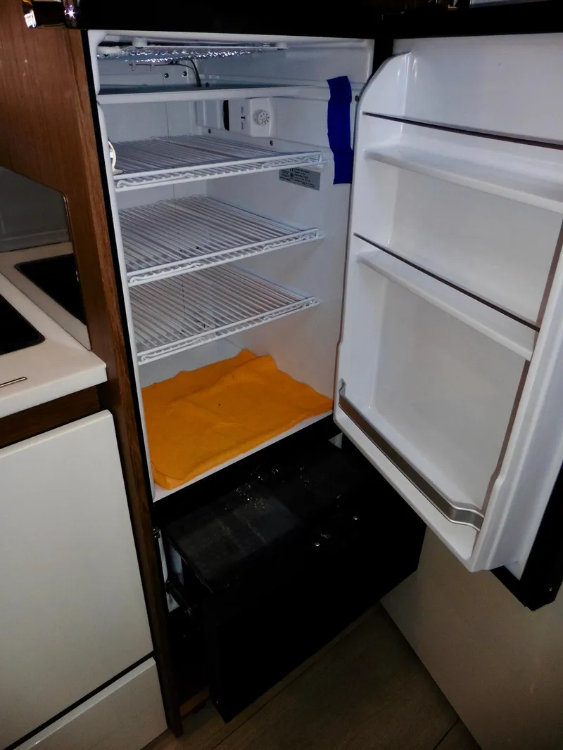 Slide: The Image of Open refrigerator inside 2017 Jeanneau Leader 46 yacht, showing empty shelves and door compartments. - 46