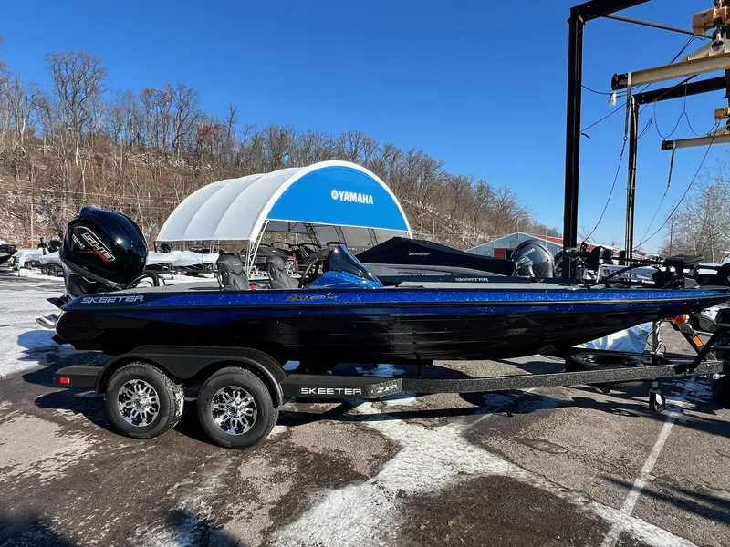 Slide: The Image of 2025 Skeeter ZXR 20 SE boat on trailer, parked outdoors, clear blue sky. - 1