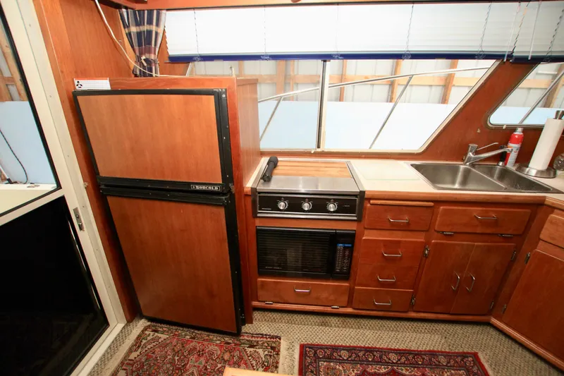 Slide: The Image of 1989 Tollycraft 34 Sport Sedan kitchen with wood cabinetry, stove, fridge, and sink. - 28