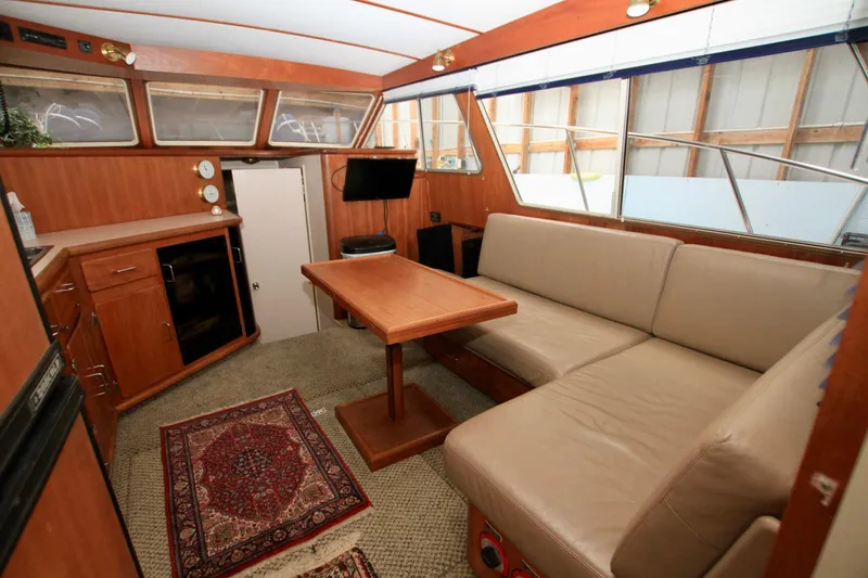 Slide: The Image of 1989 Tollycraft 34 Sport Sedan interior with beige seating, wooden table, and nautical decor. - 33