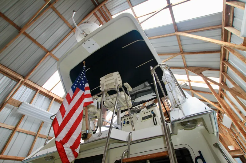 Slide: The Image of 1989 Tollycraft 34 Sport Sedan in boathouse, American flag displayed. - 43
