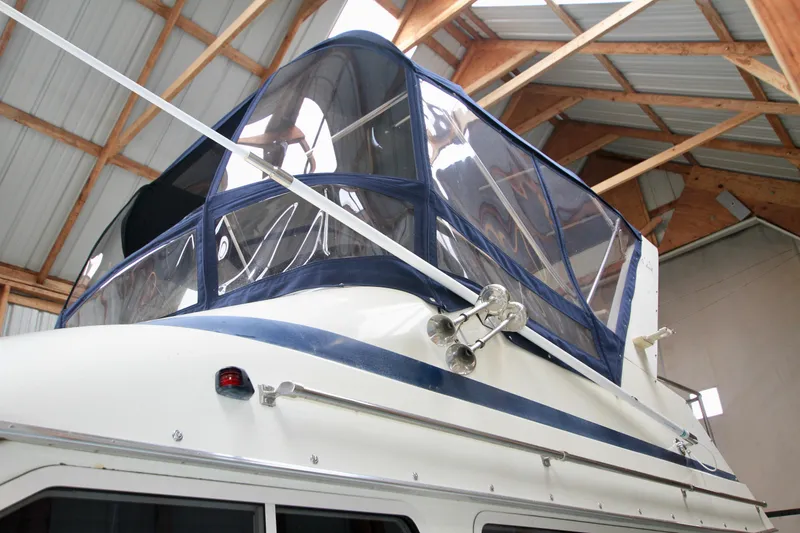 Slide: The Image of 1989 Tollycraft 34 Sport Sedan with blue canopy in a wooden boathouse. - 6