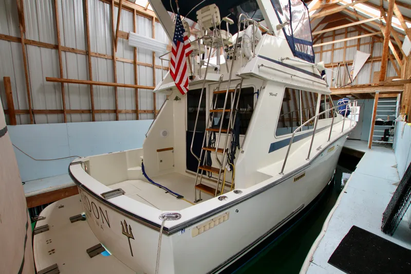 Slide: The Image of 1989 Tollycraft 34 Sport Sedan docked in a covered marina, featuring an American flag. - 8