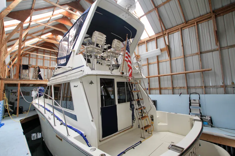 Slide: The Image of 1989 Tollycraft 34 Sport Sedan in a boathouse, featuring a flybridge and American flag. - 9