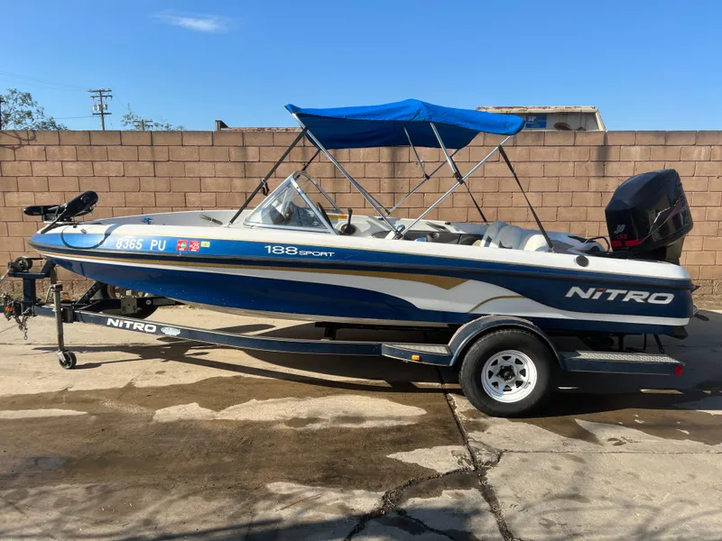 Slide: The Image of 2002 Nitro 188 Sport boat with blue canopy on trailer, parked outdoors. - 1