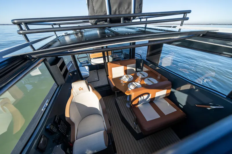 Slide: The Image of Interior of 2023 Arksen 30 boat with dining area and helm, overlooking calm waters. - 36