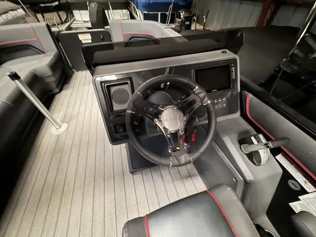 Slide: The Image of 2023 Manitou Explore 22 Max Bench boat interior with steering wheel and control panel. - 10