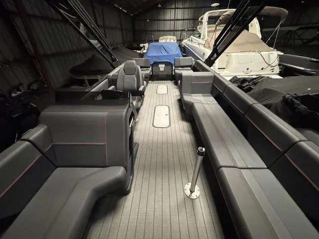 Slide: The Image of 2023 Manitou Explore 22 Max Bench boat interior with spacious seating in a storage facility. - 17