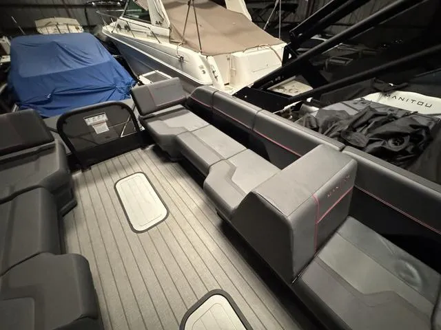 Slide: The Image of 2023 Manitou Explore 22 Max Bench interior with gray seating and spacious layout in a boat storage area. - 18