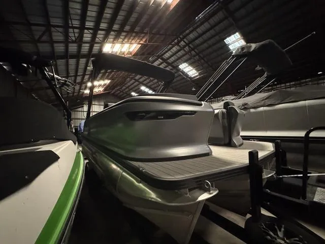 Slide: The Image of 2023 Manitou Explore 22 Max Bench pontoon boat in a dimly lit storage facility. - 3