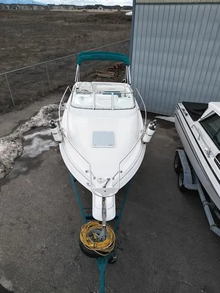 Slide: The Image of 2000 Glastron 249 boat on trailer, parked outdoors near a building. - 11