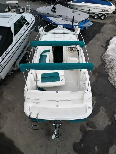 Slide: The Image of 2000 Glastron 249 boat with teal accents, docked alongside other vessels. - 12