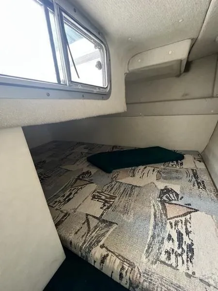 Slide: The Image of 2000 Glastron 249 cabin interior with patterned bedding and window. - 13